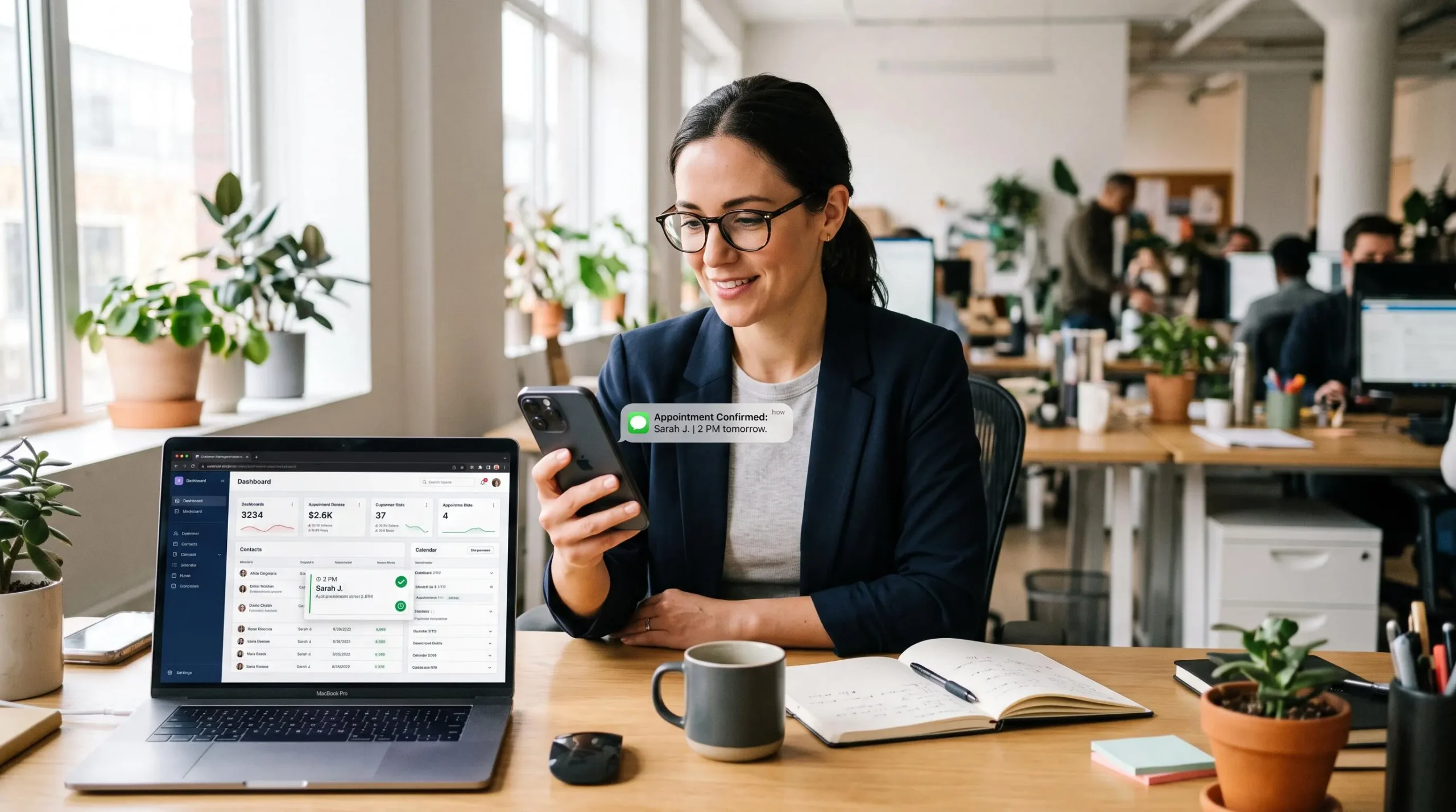 Une professionnelle consulte une confirmation de rendez-vous par SMS sur son téléphone, CRM ouvert sur l'ordinateur.